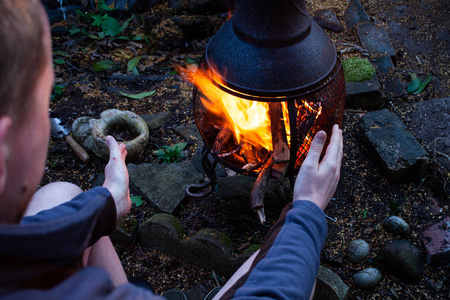 那人在开火前用手取暖.露营概念与户外明火火焰.准备烧烤火.