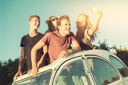 群快乐的人在夏天日落时分在一辆车以自拍照