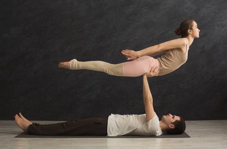 年轻夫妇在垫子上练习 acroyoga