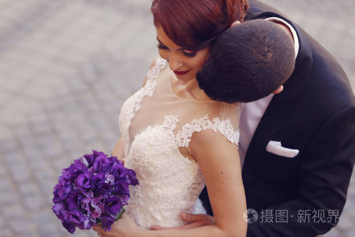 新郎的脖子亲吻他的新娘