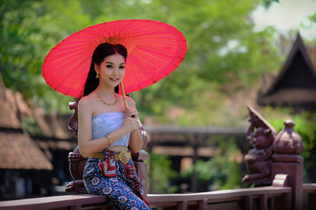 美丽的泰国女孩在传统的服装服装红色雨伞作为