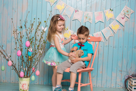 两个小小孩，男孩，女孩，和弟弟妹妹一起只兔子坐在明亮的地板上蓝色的衣服复活节，鸡蛋，节日情绪 感情和微笑惊喜的节日庆祝活动