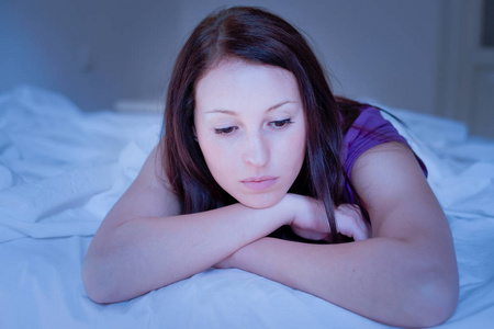 孤独的夜晚悲伤和孤独的女人躺在床上的夜晚照片