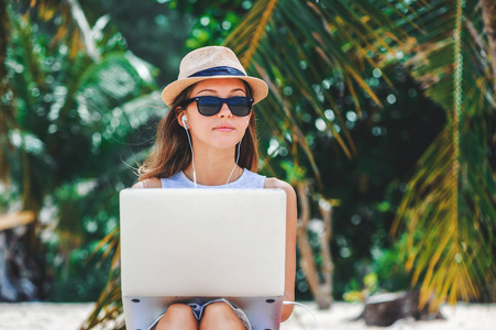 年轻女子自由职业者从事笔记本电脑在沙滩上。自由职业者的工作