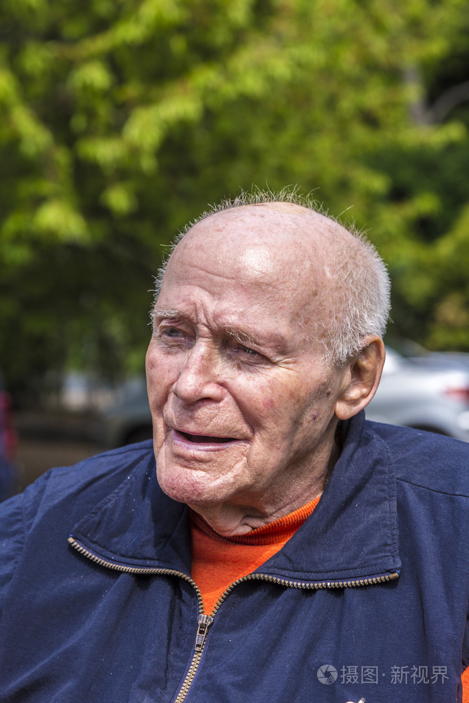 微笑着快乐的老人坐在他的花园里