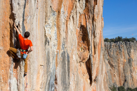 年轻的男登山者悬挂在悬崖上图片