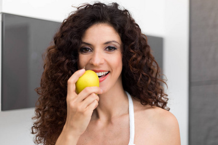 吃黄色苹果的美丽的妇女