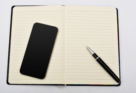 笔记本的钢笔和孤立的智能手机