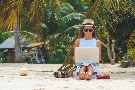 年轻女子自由职业者从事笔记本电脑在沙滩上。自由职业者的工作