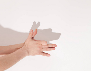 从手白墙上的影子手指显示背景上有一只狼.狗形的影子手.