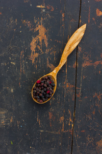 干山楂浆果在木勺老裂纹黑色的桌子上。烹饪健康饮料的成分。质朴的草药疗法的概念