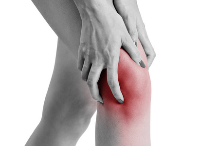 妇女抱着她的膝盖与红色突出显示疼痛区域, 黑白颜色隔离白色背景照片