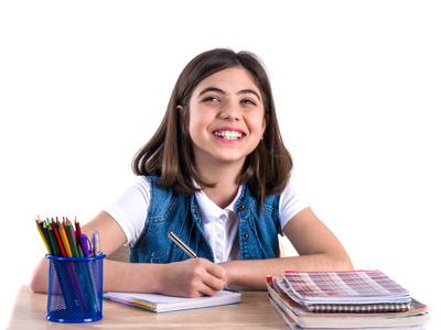 一个漂亮的学生女孩坐在课桌前写着信。