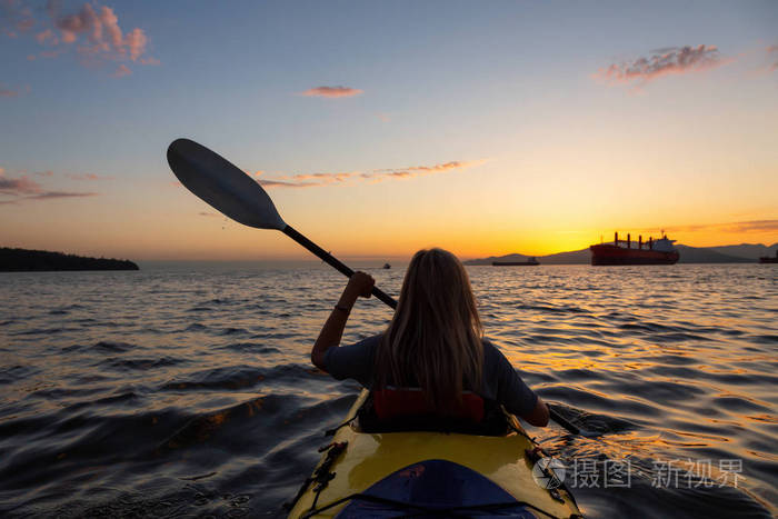 一只独木舟上的女人在 paddeling 的日落时被大海所影响。在加拿大不列颠哥伦比亚省温哥华拍摄。概念 冒险, 假日, 生活