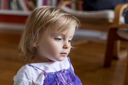 严重的悲伤或思维年幼的婴儿白种人的金发女孩肖像在家里
