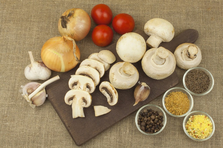 在砧板上的生蘑菇。香菇在厨房里准备。准备食物的香料。蔬菜准备饭菜