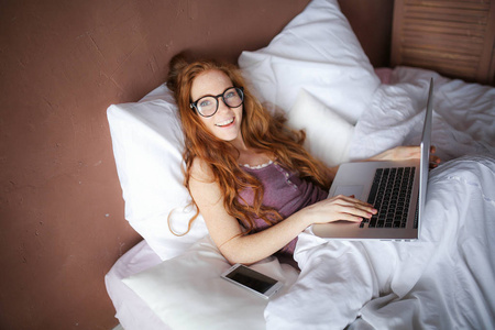 女人躺在床上时使用的笔记本电脑