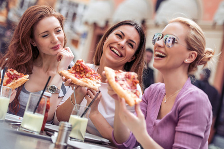 三快乐的女孩在户外咖啡馆吃比萨饼。人食物饮料和生活方式概念