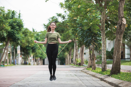 合适的年轻女人,与在公园里跳绳照片