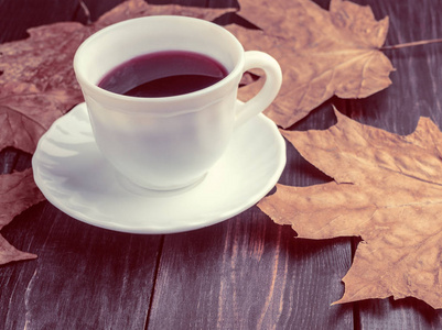 老木板上有咖啡的白杯子和五颜六色的秋叶