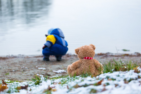 小男孩和湖岸上的泰迪熊