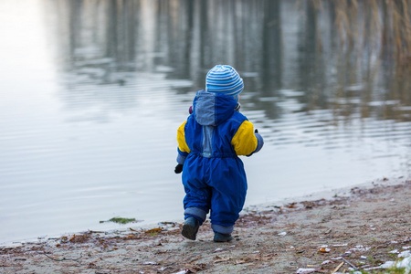 在结冰的湖岸上玩户外的小男孩