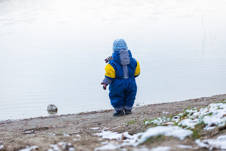 在结冰的湖岸上玩户外的小男孩