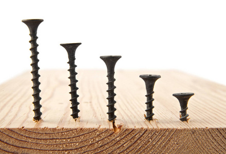 在白色背景上的木板上的螺丝照片