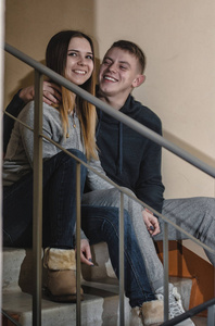 十几岁的男友和女友坐在公寓楼的台阶上。