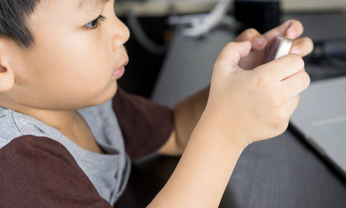 亚洲男孩使用智能手机玩游戏图片
