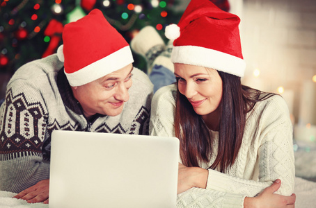 快乐的家庭与笔记本电脑在圣诞树背景