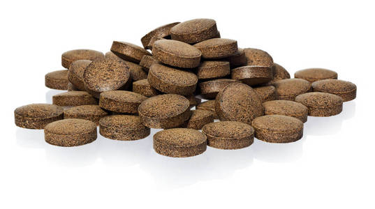 印度草药药材.棕色的药片, 在白色背景下被照片