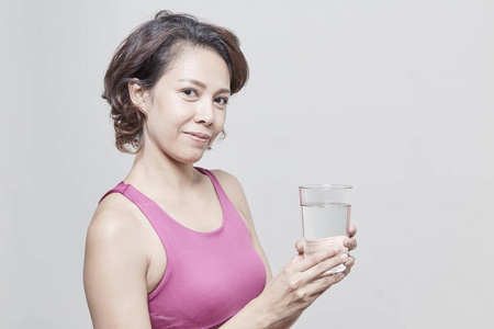 亚洲短发妇女手持一杯水在运动服装, 减肥概念