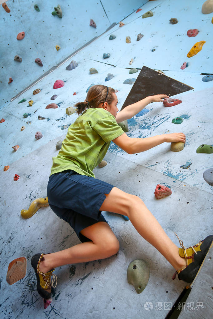 少年男孩训练攀登在室内攀岩墙上