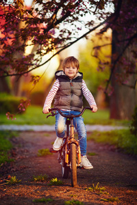 可爱的孩子，骑着自行车穿越春天公园