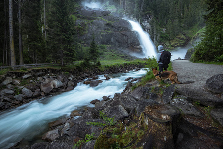 人和狗看 Krimml 瀑布在高 Tauern 国家公园奥地利