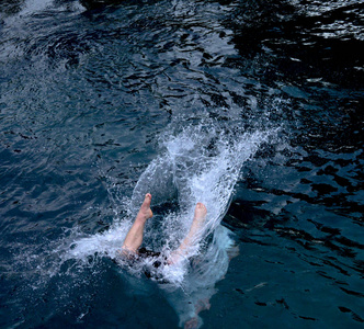 跳入水中当他跳入水中时,他把雌性溅到游泳池里女潜水员站在跳跃板上