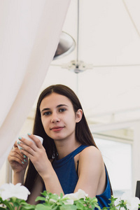一个非常美丽的商业女人坐在咖啡馆里, 手里拿着一杯咖啡。