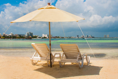 在坎昆海滩上为游客准备的太阳躺椅和白色雨伞。墨西哥