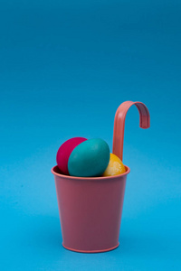 复活节彩蛋在孤立的蓝色背景上的粉色桶