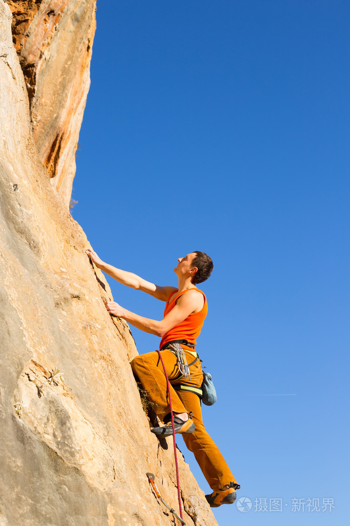 年轻的男登山者悬挂在悬崖上照片-正版商用图片0oxmzb-摄图新视界
