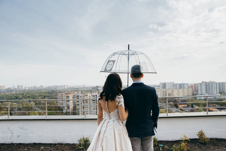 一对年轻漂亮的新婚夫妇带着雨伞