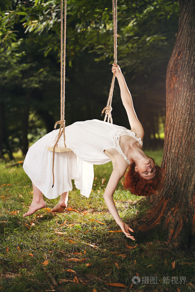 鞠躬在秋千上的美丽女人