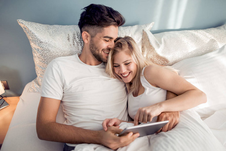 幸福夫妻穿着睡衣在家使用平板电脑的爱