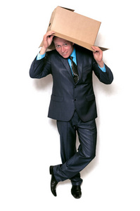 快乐的商人把他的脸藏在头顶上的纸板箱里, 从那里偷看白色背景。