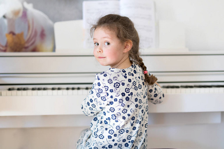 漂亮的小孩小女孩弹钢琴在客厅或音乐学校