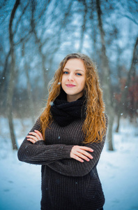 欧洲人的年轻女孩与红色的头发和蓝色的眼睛在自然公园里冬天走在雪上