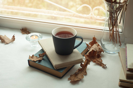 温暖舒适的场景与老书, 杯茶和蜡烛在桌子上.