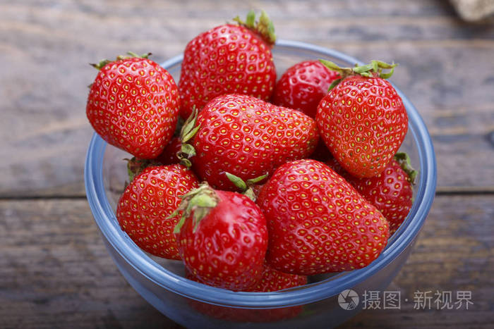 成熟的草莓在一块玻璃板上木制的背景