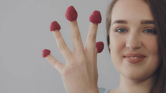 年轻的白种女人直长头发吃树莓从手指